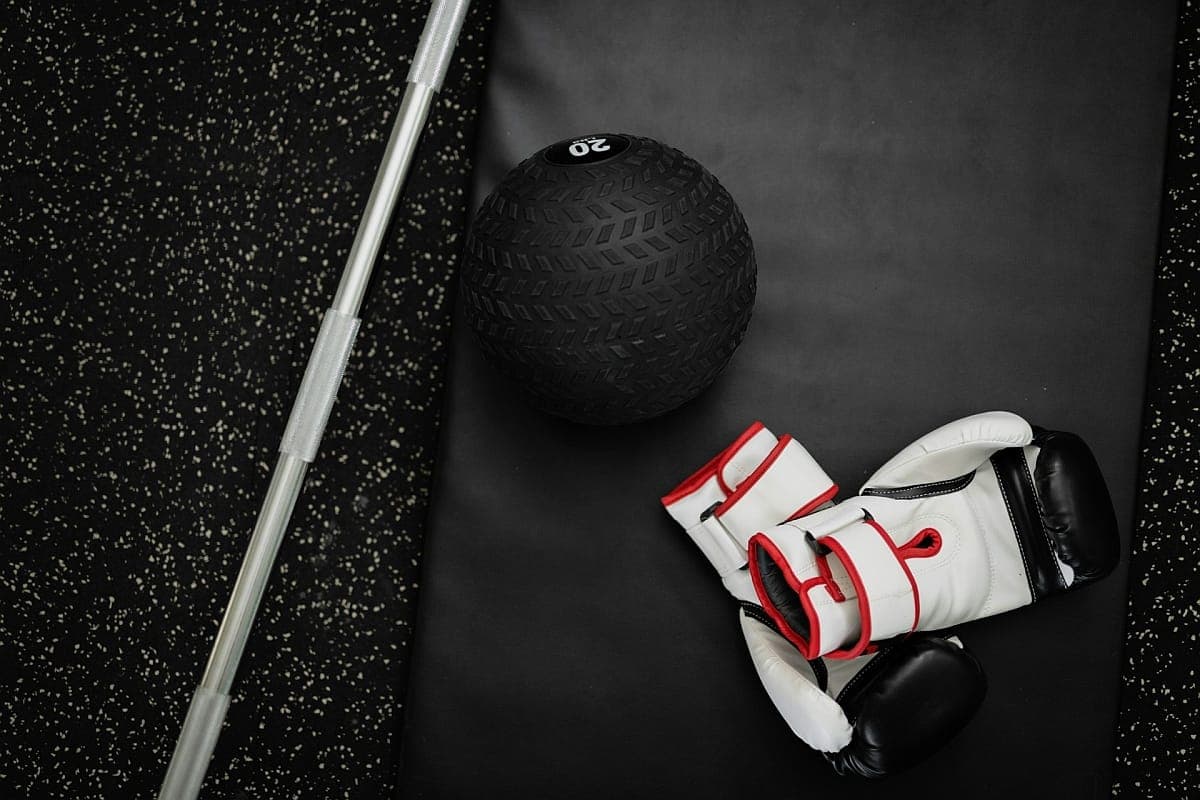 Bokshandschoenen naast een medicijnbal op de vloer van een sportschool